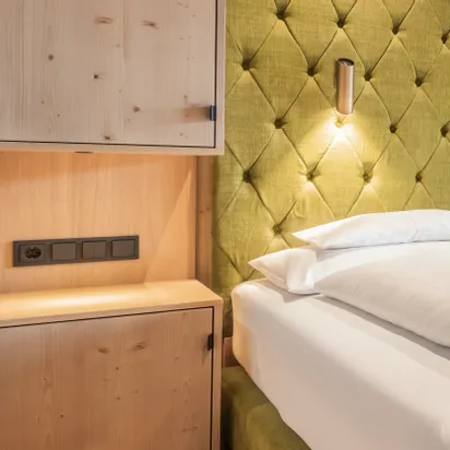 Modern hotel room with green tufted headboard and light wood furniture